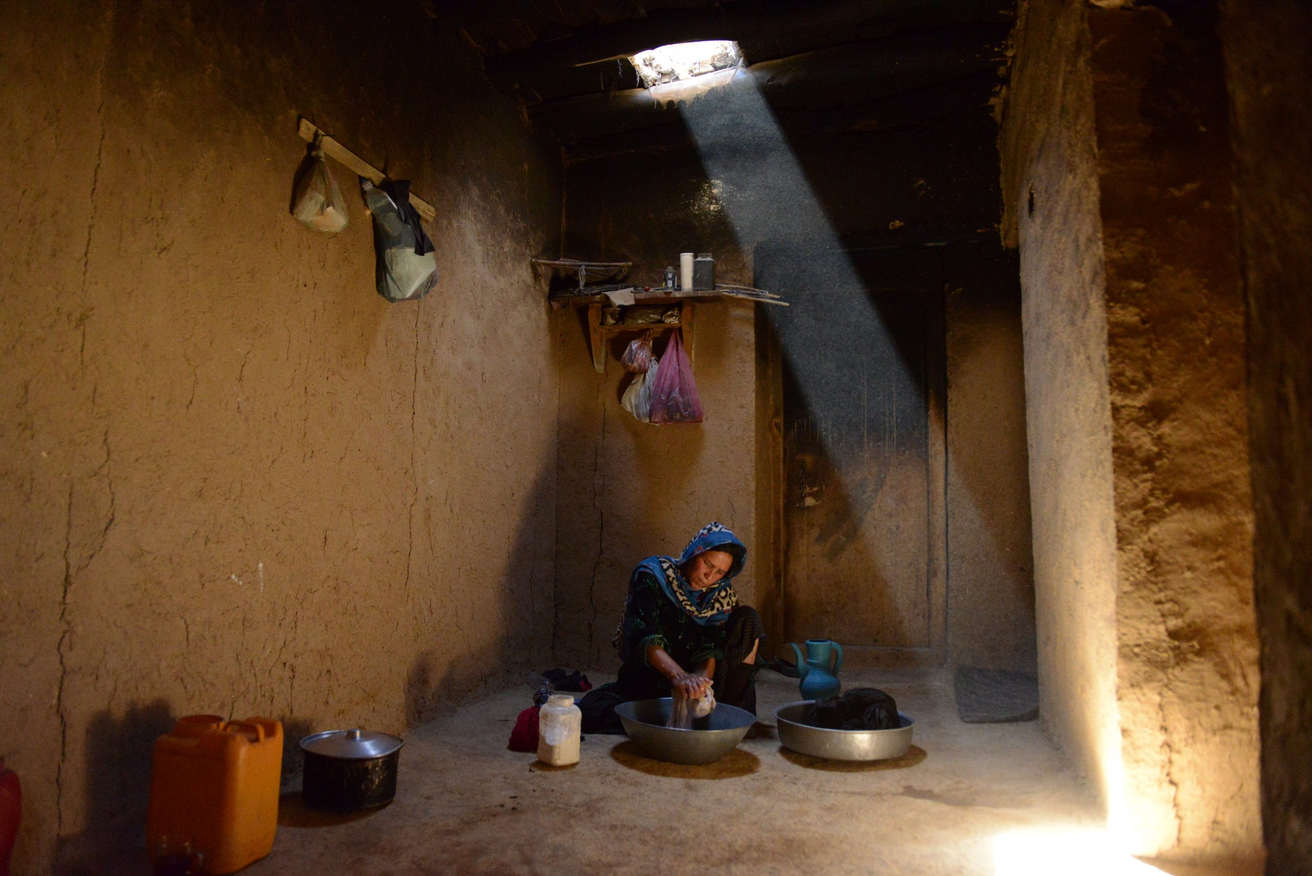 Una donna afghana lava i panni nella sua casa nella provincia di Bamiyan, dove la maggior parte delle persone vive in strutture fatiscenti e con poche risorse. 2016.. ©Najiba Noori