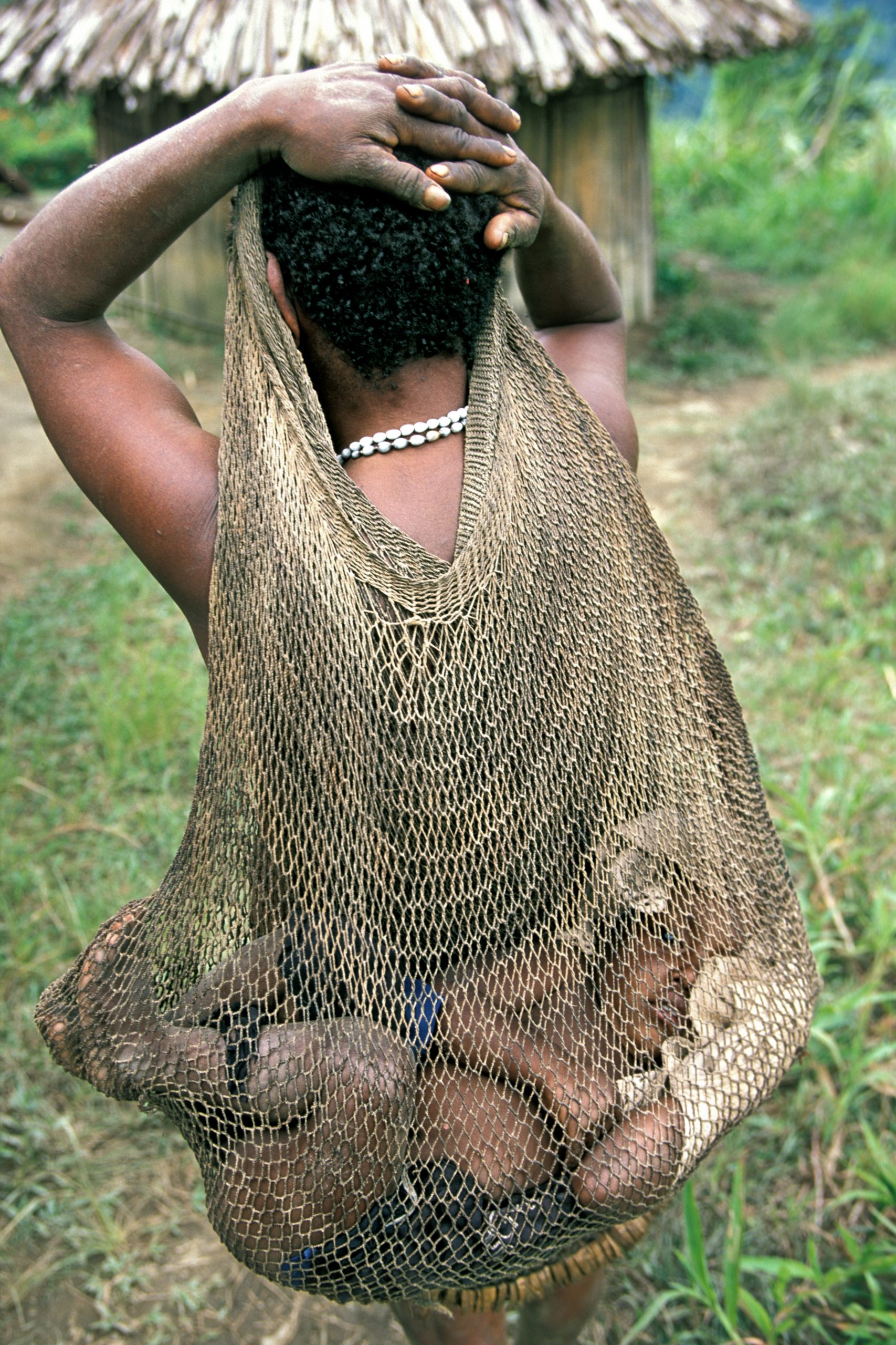 Papua Highland - West Papua - Una bambina Yali portata nella borsa dalla madre. La terra dove vivono gli Yali è una delle più impervie e isolate al mondo e la tribù è entrata in contatto con il resto del mondo solo pochi decenni fa. ©Bruno Zanzottera